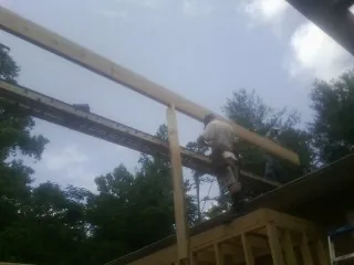 Carpenter setting a ridge beam over a new addition frame — Ice Dam Removal by Roofing Brothers in Winchester